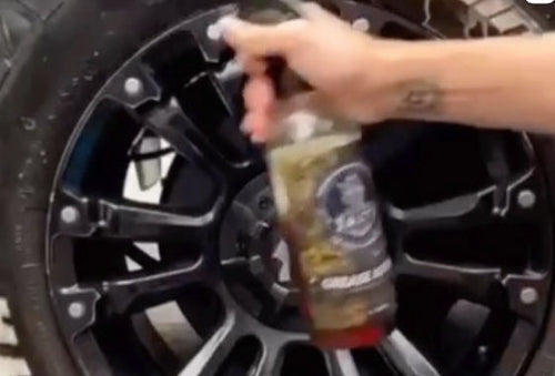 "Salty Captain's Grease Attack bottle with a wheel and tire in the background, representing a powerful solution for wheel cleaning and white lettering restoration."